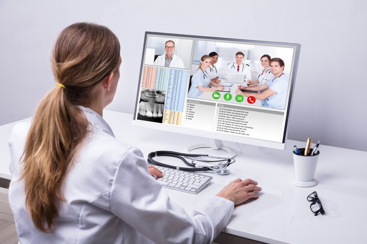 Doctor Video Conferencing With Colleagues On Computer